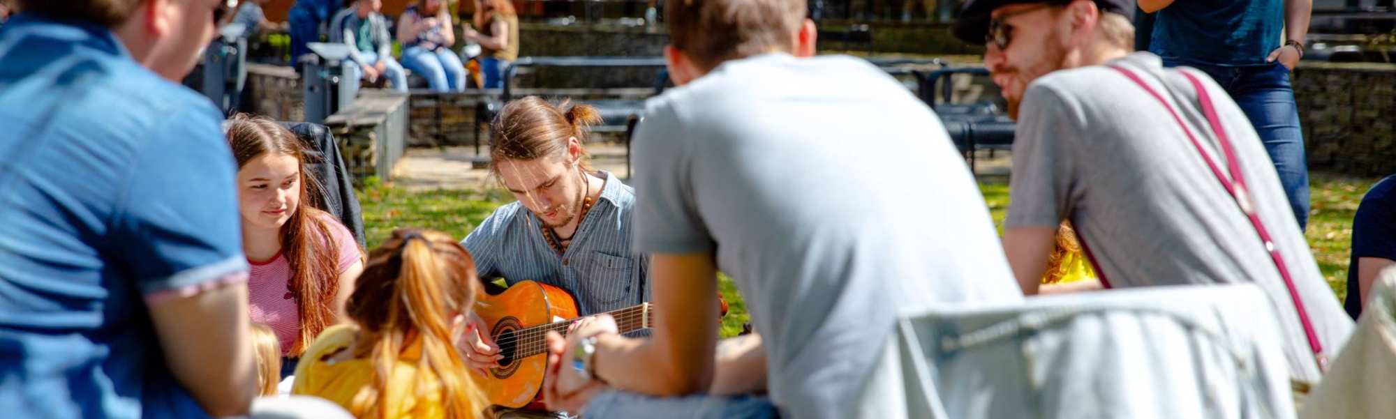 Groep studenten buiten met gitaar