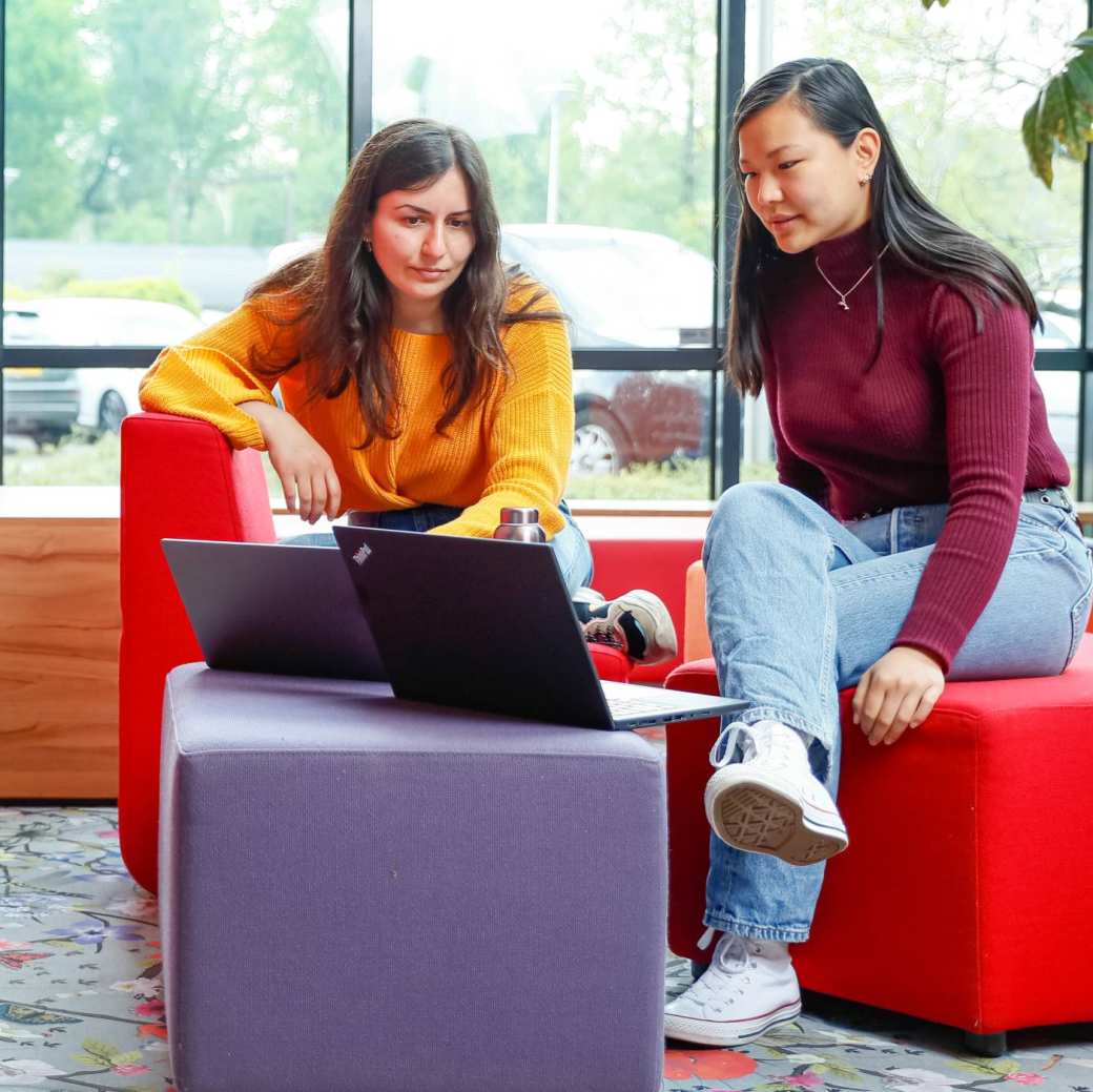 348204 Twee internationael studenten overleggen met laptop bij rode banken