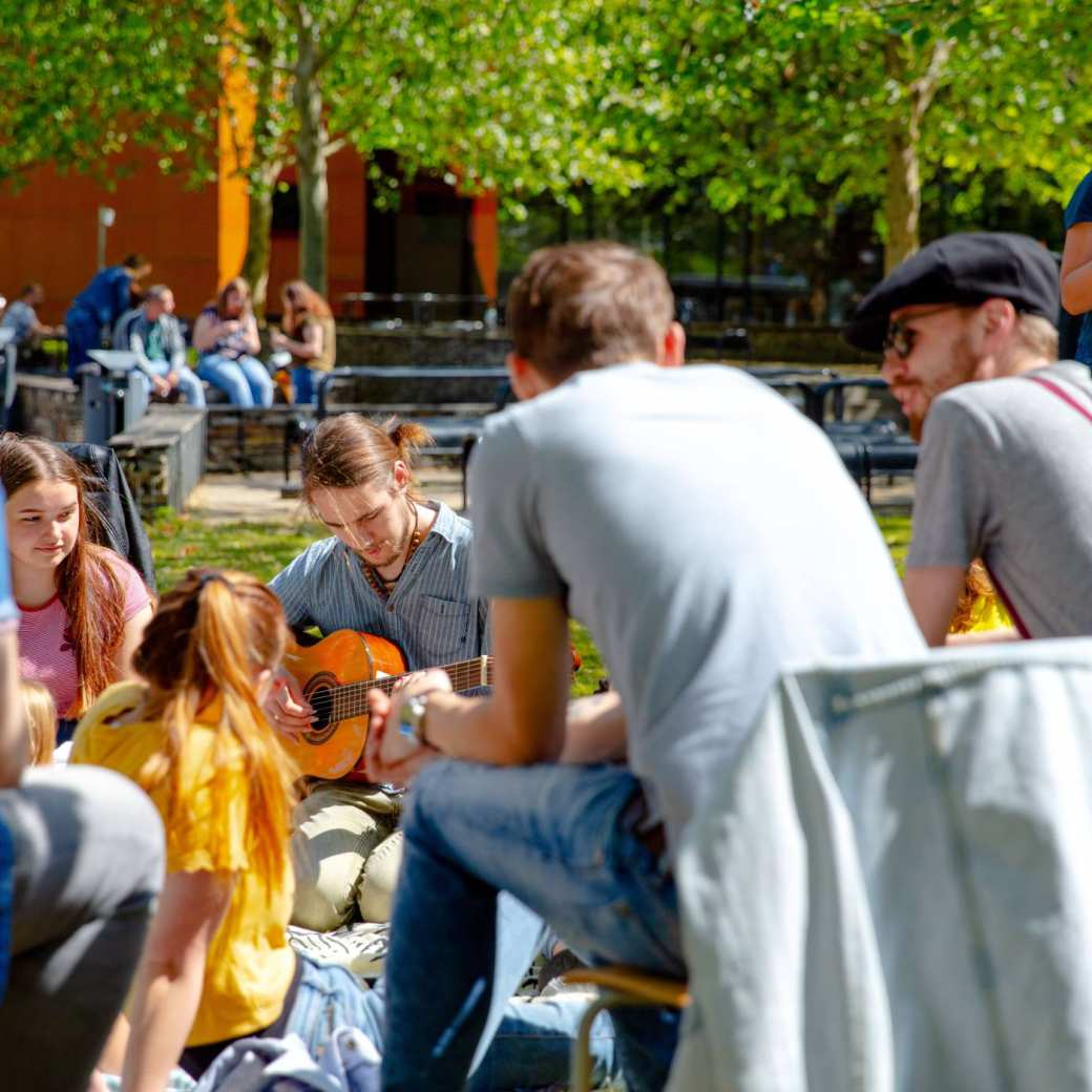 35020 Groep studenten buiten met gitaar