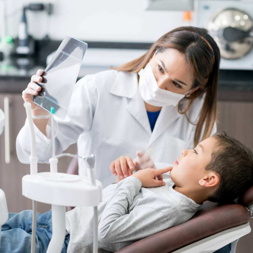 tandarts op zoek naar een rÃ¶ntgenfoto met zijn jonge patiÃ«ntÂ 