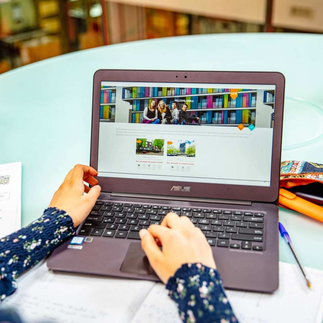 Student achter laptop met book your room app