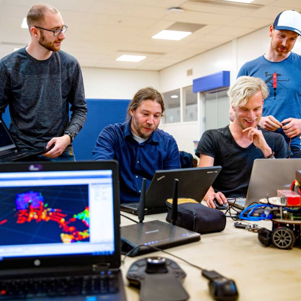 Master of Engineering students are programming a miniature autonomous vehicle with a laptop