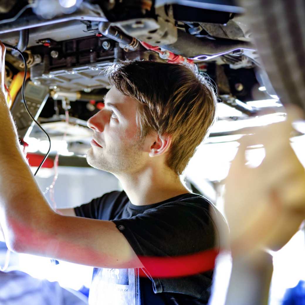 Twee studenten werken aan auto op hefbrug