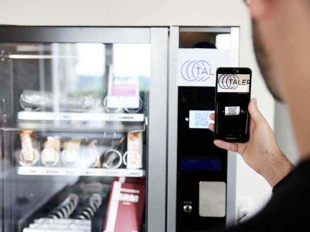 Man betaalt bij de snackautomaat met de GNU-taler app op zijn telefoon