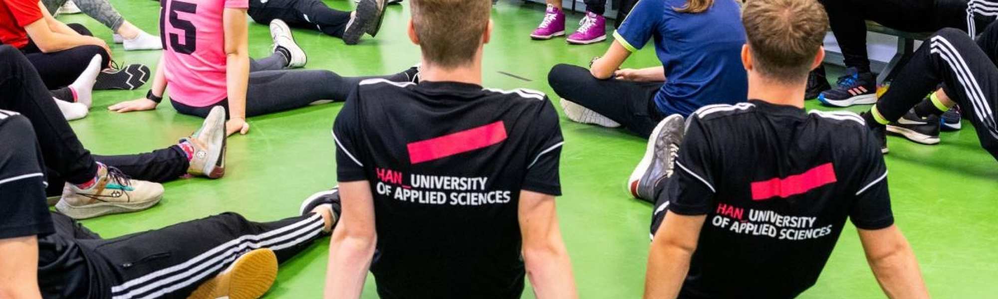 Studenten luisteren in de sportles naar docente.