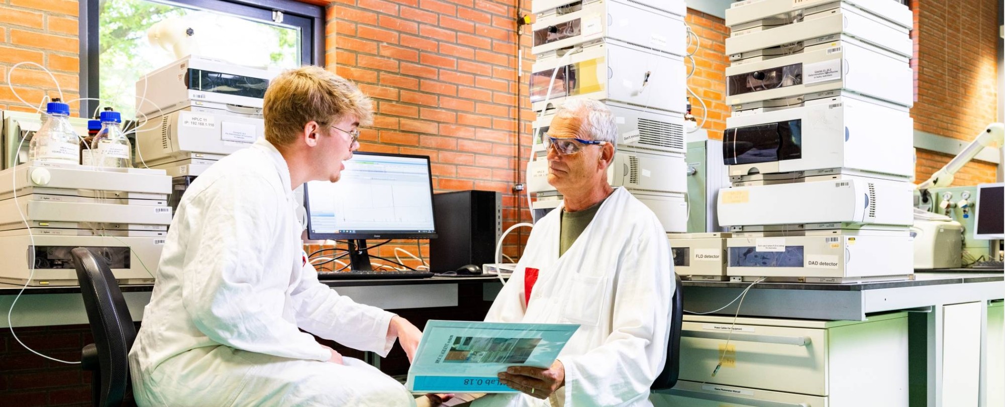 docent geeft uitleg aan student in chemie lab