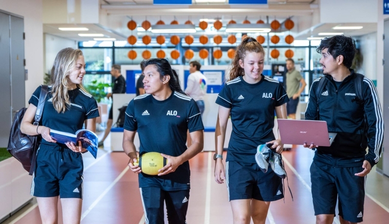 sportkunde en alo samen liggende foto studenten lopen over atletiekbaan binnen bij gymnasion selena esteban carlijn randy 2022