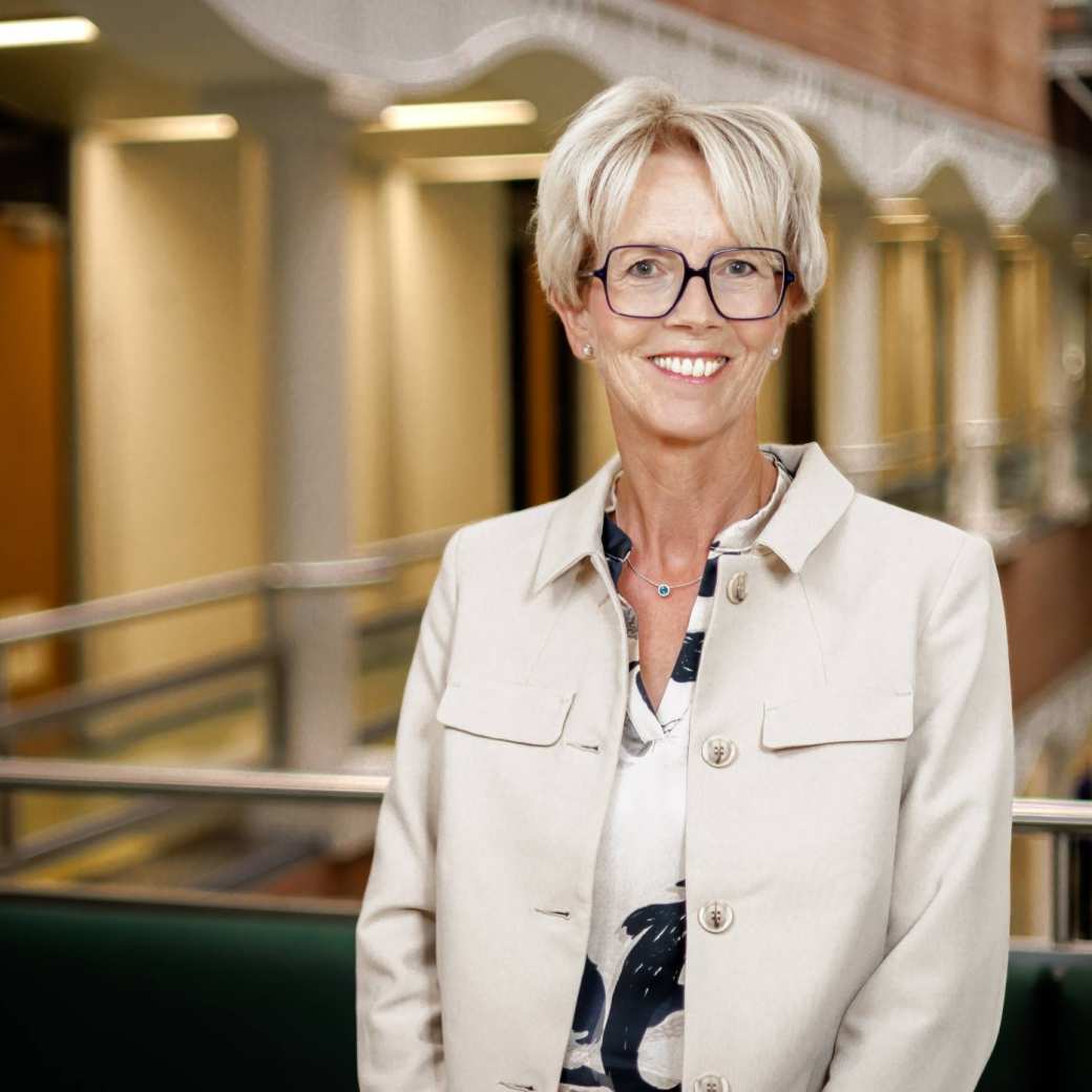 Aly Smelt, een vrouw met kort blond haar, een bril en een cremekleurig jasje