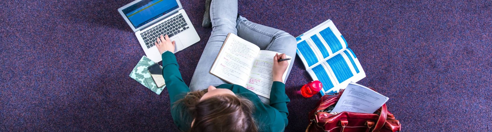 Studente studeren in studiecentrum en werken op laptop, van bovenaf