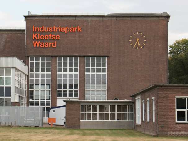 Gebouw op IPKW in Arnhem met klok en oranje letters 