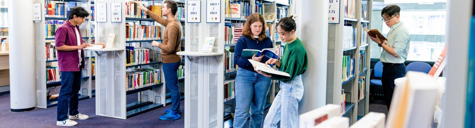 International students browsing through study books in the library on the Arnhem campus of HAN University of Applied Sciences.