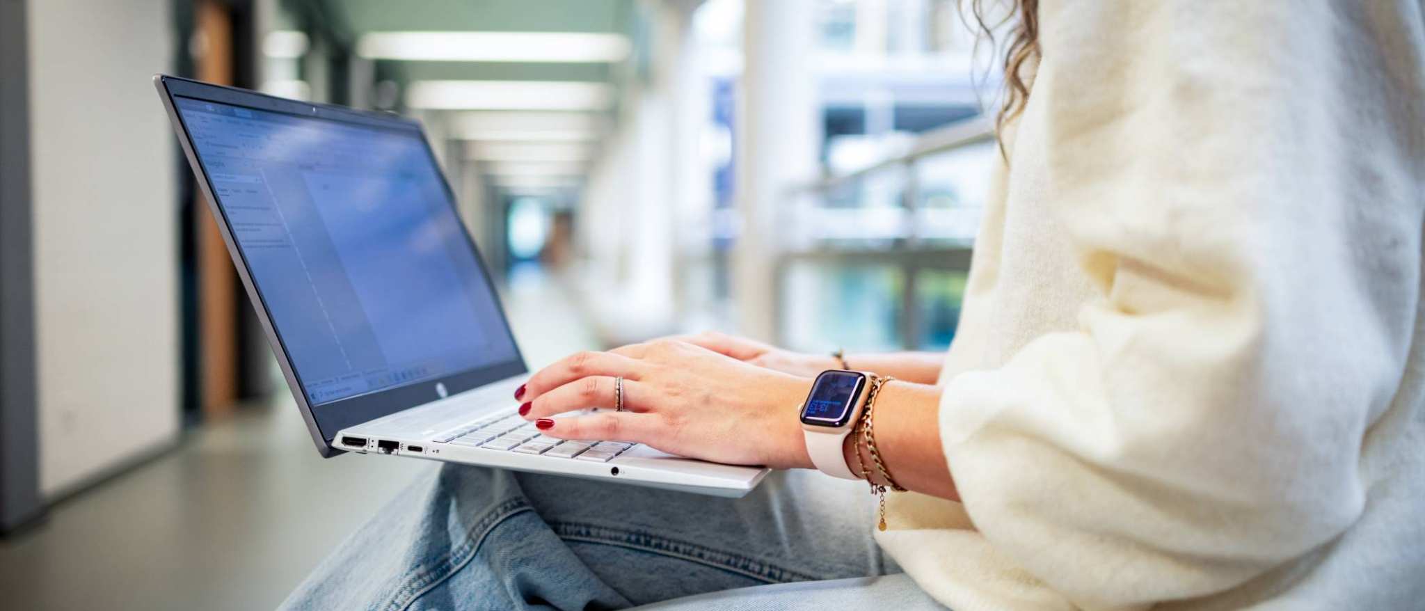 Student van de bachelor Commerciële Economie deeltijd, duaal in gang met laptop.