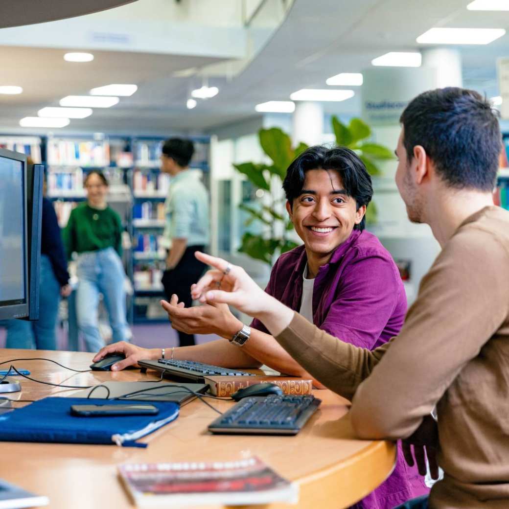 International students Diego and Andrei looking for information in the library at the Arnhem campus of HAN University of Applied Sciences.