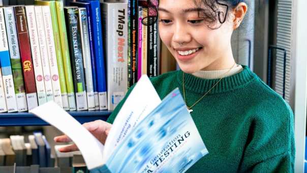International student Tam browsing through study books in the library on the Arnhem campus of HAN University of Applied Sciences.