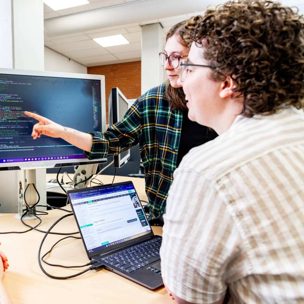 2 Bioinformatics students pointing at a computer screen.