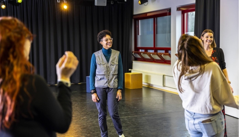 Studenten international social work in drama lokaal. In het midden een student met zwarte krullen en een grijze bodywarmer.