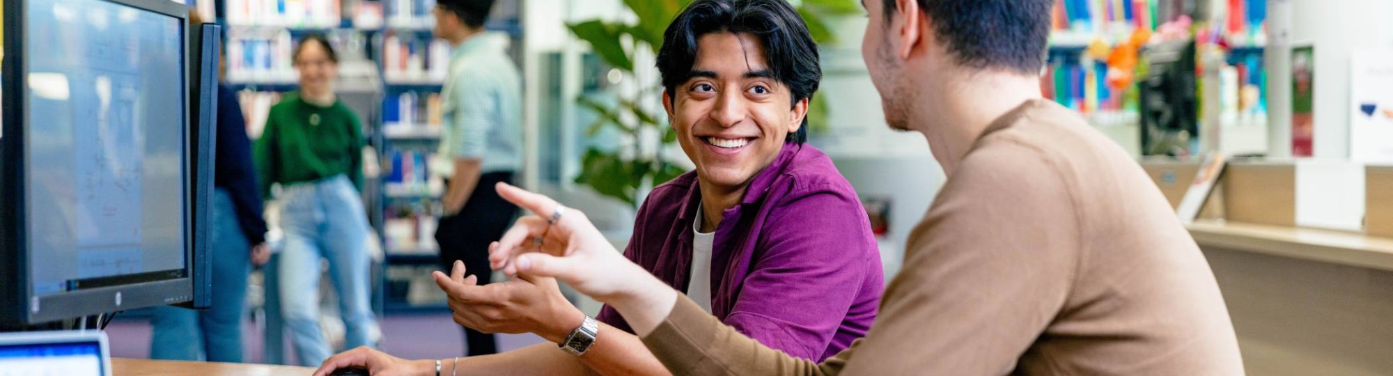 International students Diego and Andrei looking for information in the library at the Arnhem campus of HAN University of Applied Sciences.