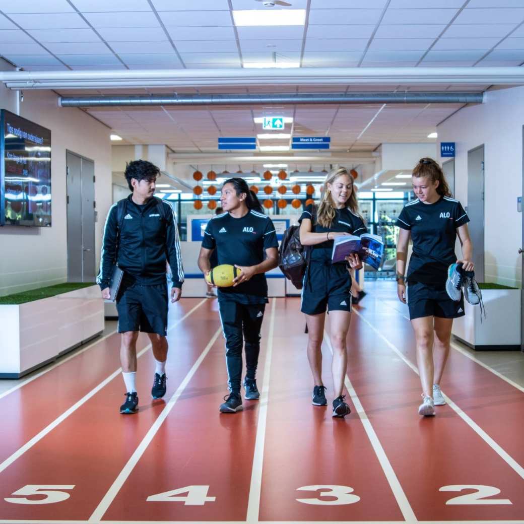 sportkunde en alo samen liggende foto studenten lopen over atletiekbaan binnen bij gymnasion veraf esteban selena carlijn randy 2022