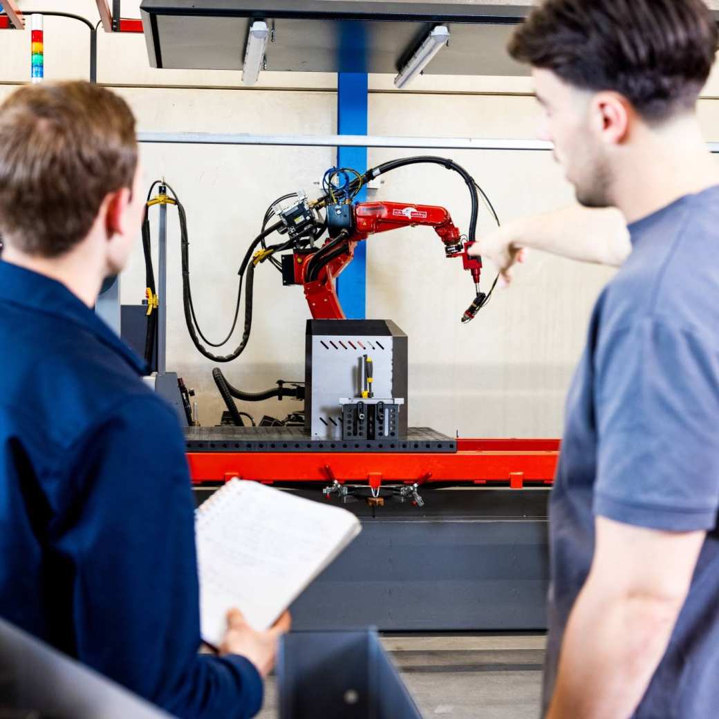 Technische Bedrijfskunde studenten Jort en Derk samen bij robot arm.