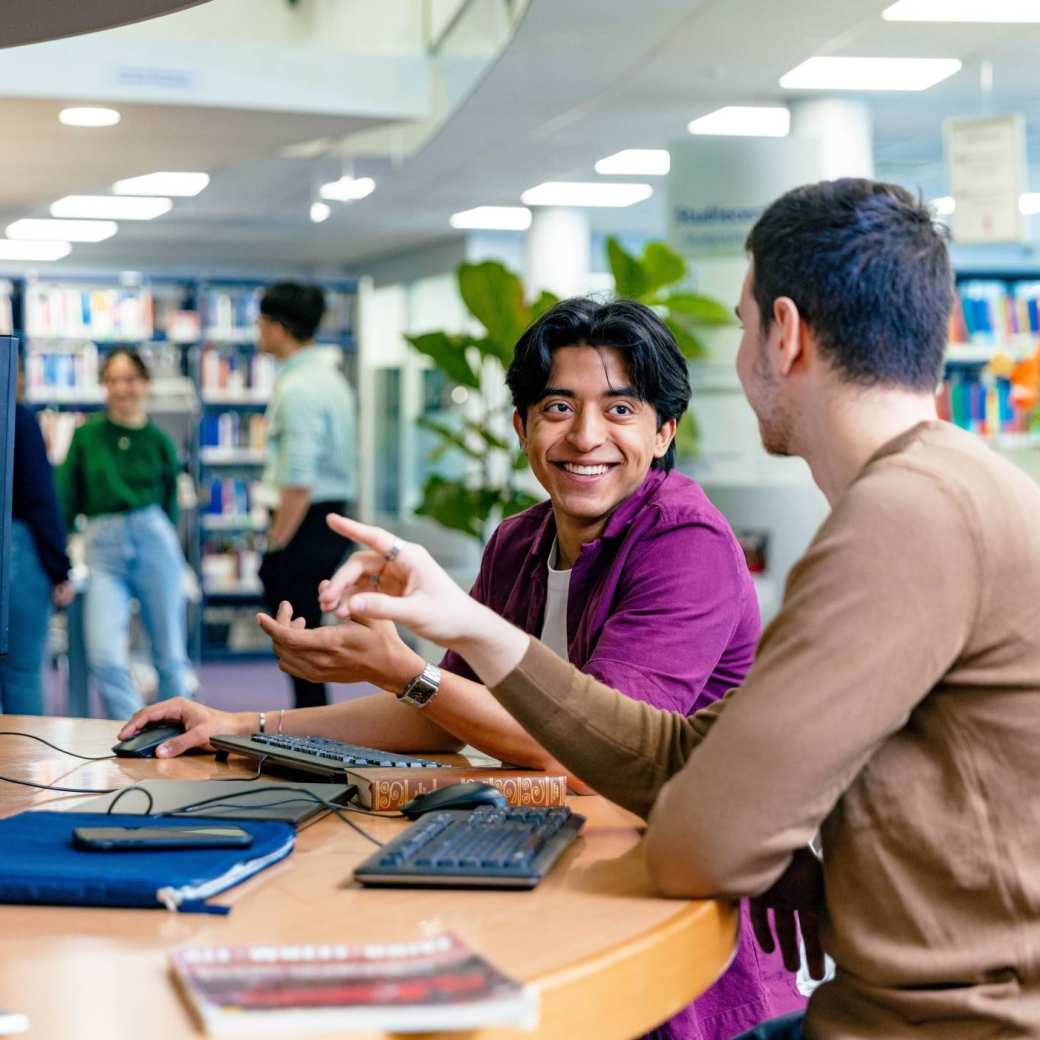 International students Diego and Andrei looking for information in the library at the Arnhem campus of HAN University of Applied Sciences.