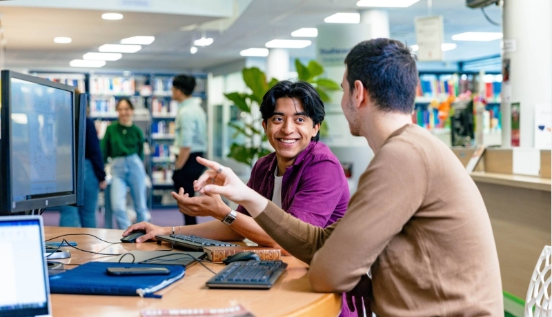 International students Diego and Andrei looking for information in the library at the Arnhem campus of HAN University of Applied Sciences.
