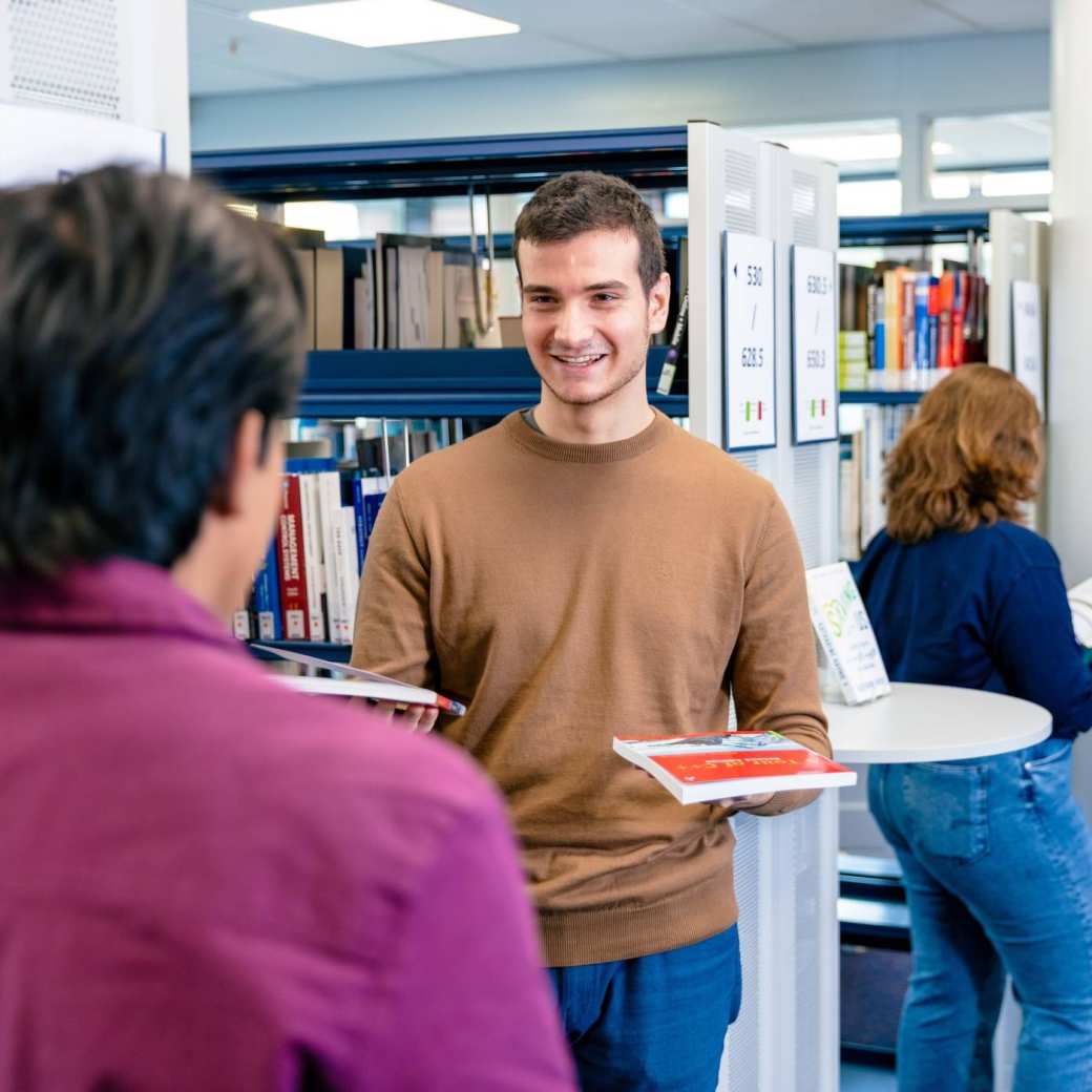 International students Diego, Andrei, Noa and Tam browsing through books in the library on the Arnhem campus of HAN University of Applied Sciences.