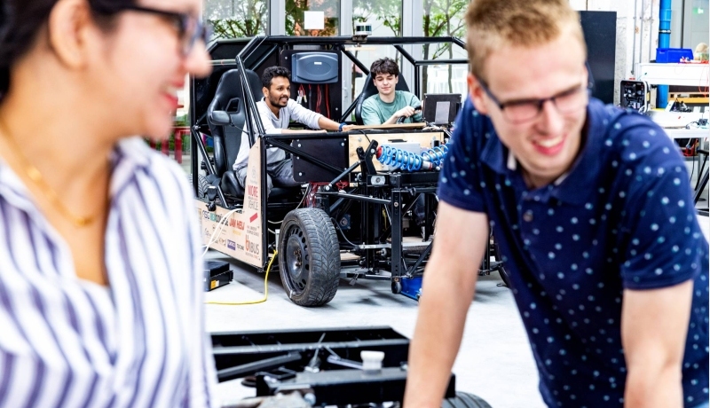 Studenten en docent van de master Engineering Systems Automotive Systems met de MORE Vehicle op de achtergrond.