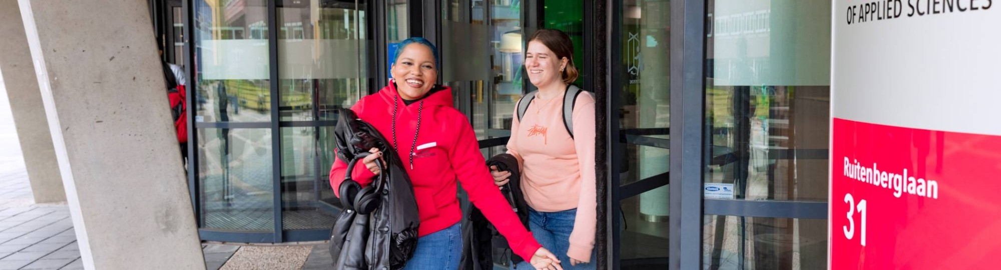 Noa and Chadionne walking through the entrance by Ruitenberglaan 31 HAN Arnhem campus.