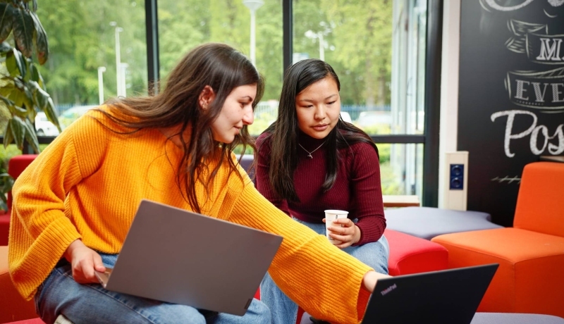 Twee studenten met laptop overleggen en wijst naar scherm