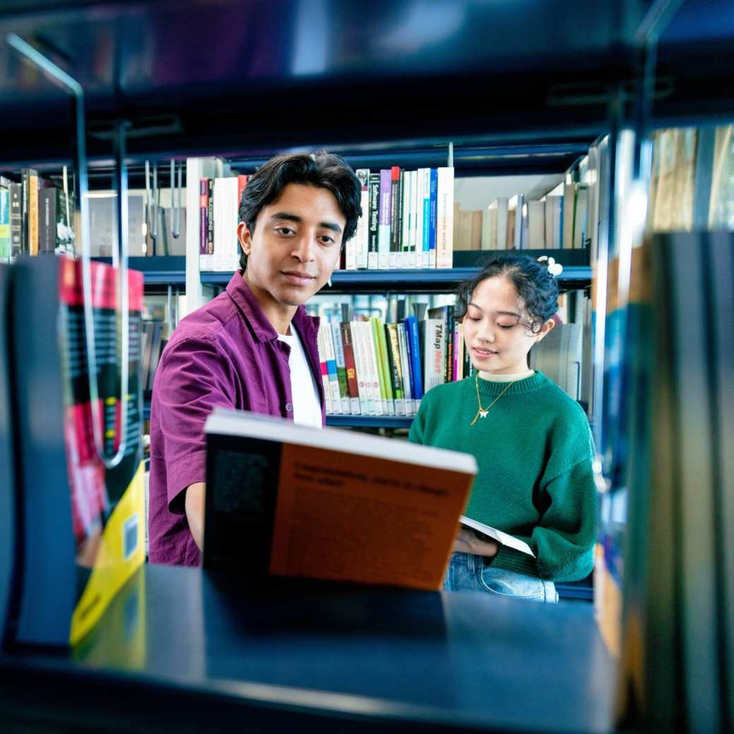International students Diego and Tam looking for books in the library on the Arnhem campus of HAN University of Applied Sciences.