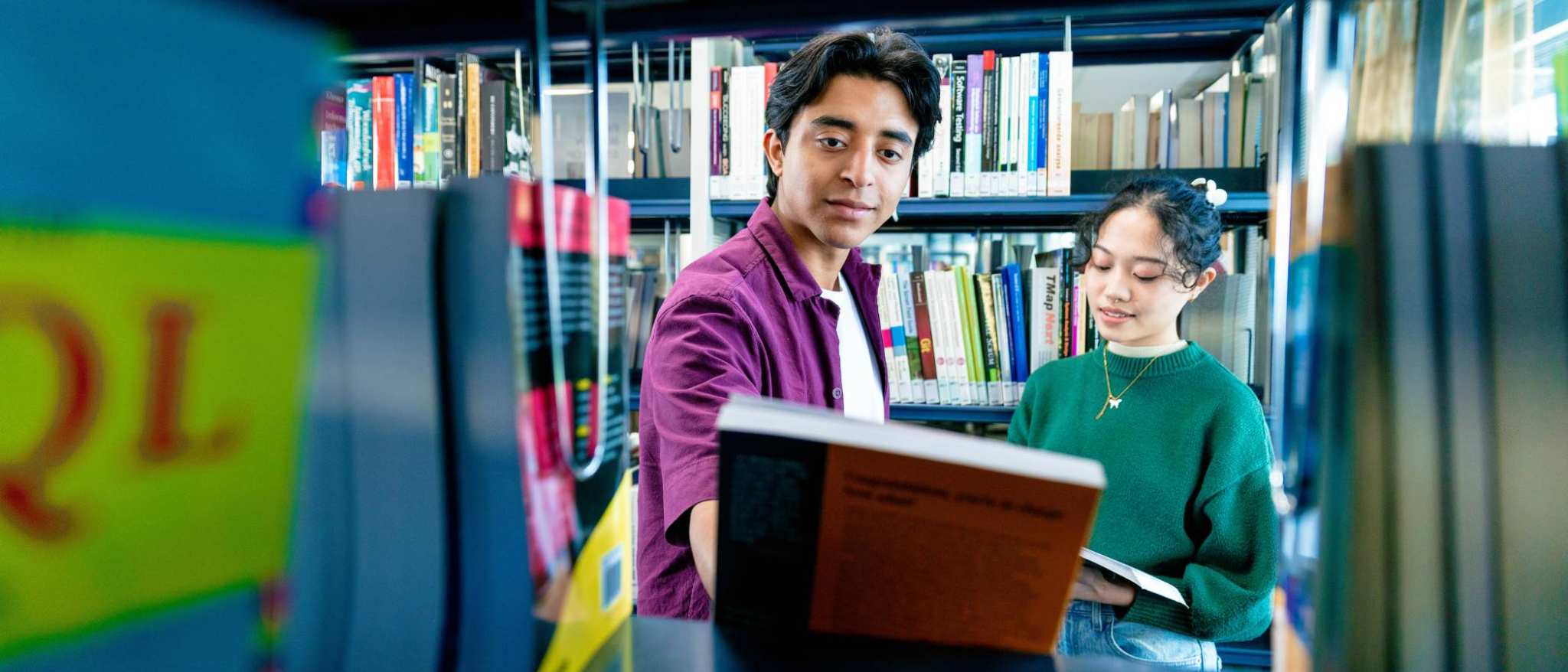 International students Diego and Tam looking for books in the library on the Arnhem campus of HAN University of Applied Sciences.