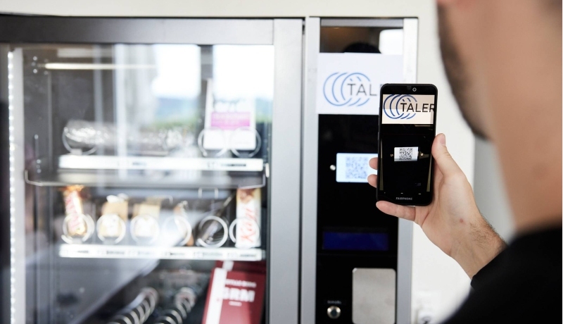 Man betaalt bij de snackautomaat met de GNU-taler app op zijn telefoon