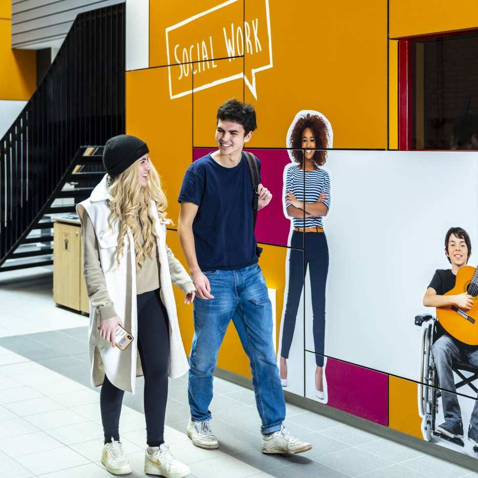 International Social Work. Twee studenten lopend in de gang van kapittelweg 33.
