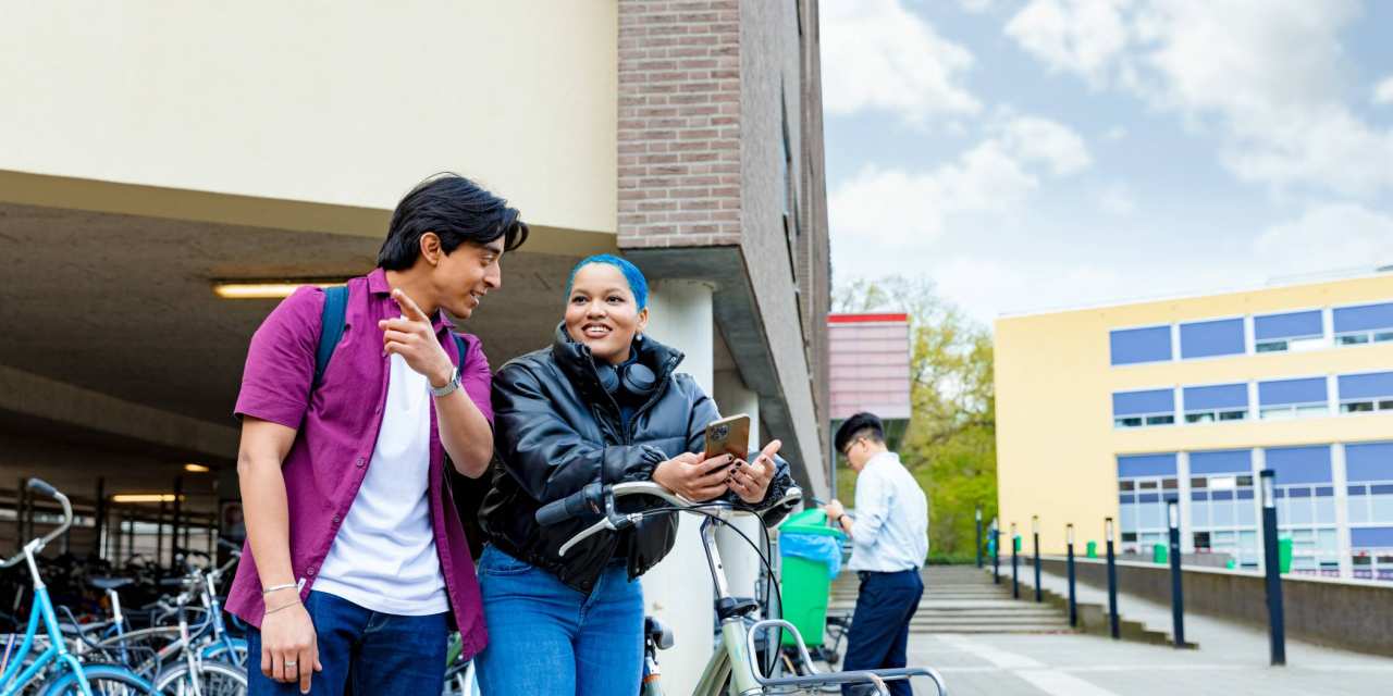 International students Diego and Chadionne with their bikes looking for directions on the Arnhem campus of HAN University of Applied Sciences.